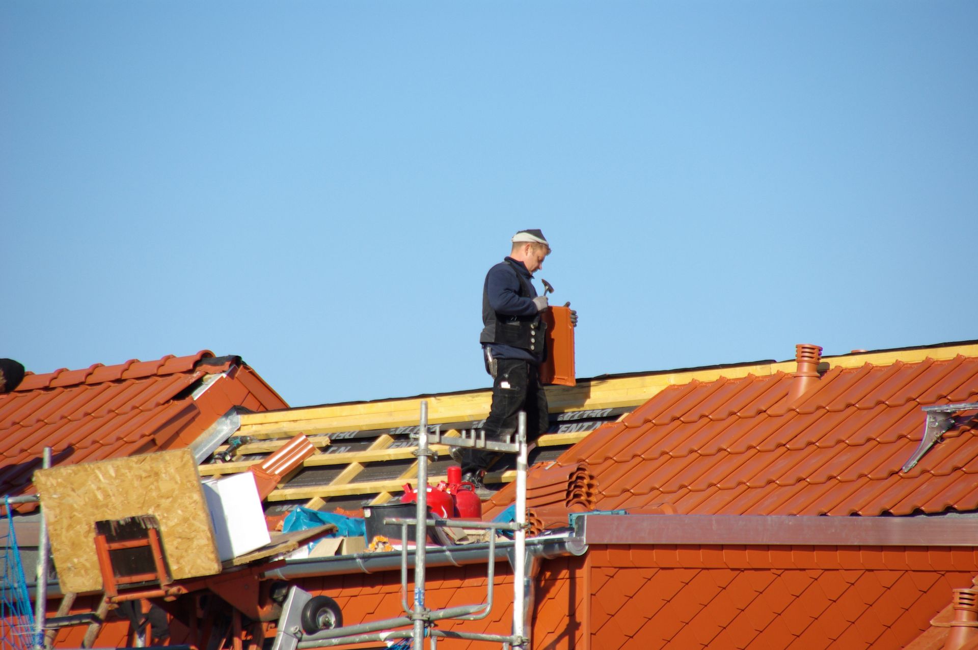 Carpenter working on roof construction against a blue sky